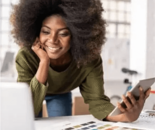 Woman smiling while using phone and laptop.